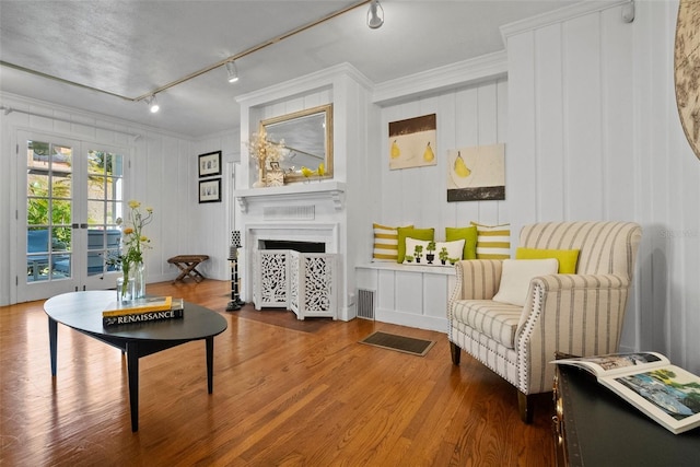 living area featuring track lighting, wood finished floors, french doors, a large fireplace, and crown molding