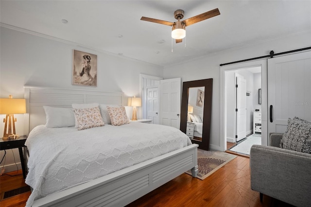 bedroom featuring ceiling fan, a barn door, hardwood / wood-style floors, and ornamental molding