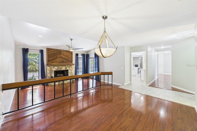1776 E Cheryl Dr, Winter Park, FL 32792 - unfurnished living room with wood finished floors, ceiling fan, a stone fireplace, and baseboards