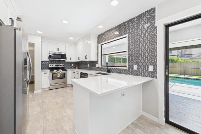 1776 E Cheryl Dr, Winter Park, FL 32792 - kitchen featuring stainless steel appliances, a sink, a peninsula, white cabinets, and light countertops