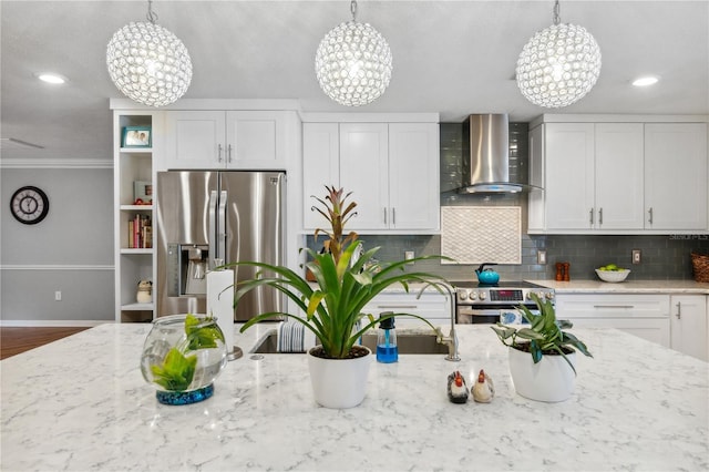 kitchen featuring tasteful backsplash, appliances with stainless steel finishes, wall chimney exhaust hood, light stone countertops, and a chandelier