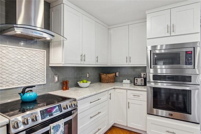 kitchen with white cabinetry, electric range, wall chimney exhaust hood, and tasteful backsplash