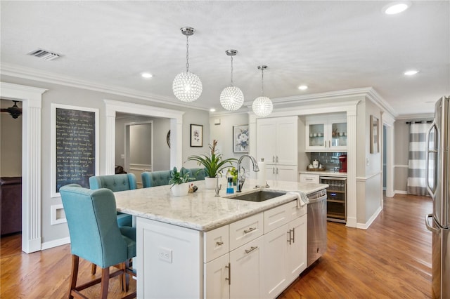 kitchen featuring a sink, wine cooler, appliances with stainless steel finishes, white cabinetry, and a kitchen breakfast bar