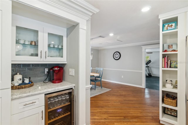 bar featuring beverage cooler, baseboards, light wood finished floors, ornamental molding, and decorative backsplash