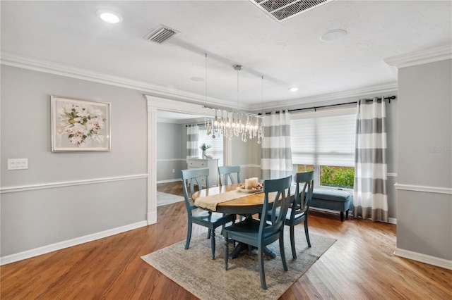 dining area featuring visible vents, wood finished floors, a chandelier, and crown molding