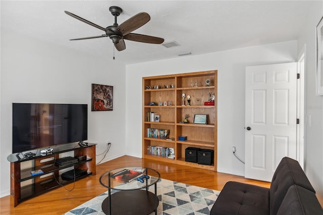 living room featuring visible vents, baseboards, ceiling fan, and wood finished floors