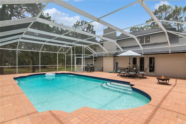 pool with grilling area, a patio, a fire pit, and a lanai