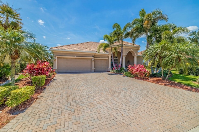 mediterranean / spanish house with a tiled roof, stucco siding, driveway, and a garage