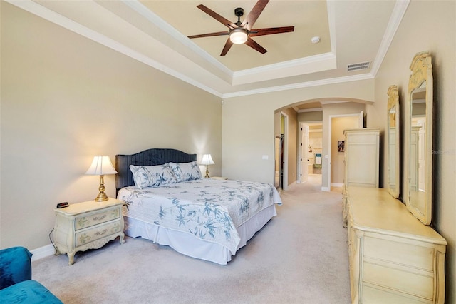 bedroom with visible vents, ornamental molding, a raised ceiling, arched walkways, and light colored carpet
