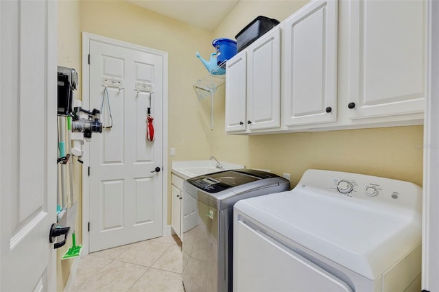laundry area with washer and dryer, cabinet space, a sink, and light tile patterned floors