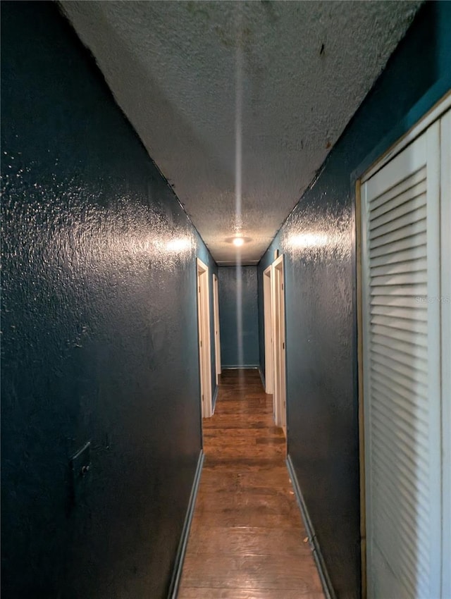 5195 Edwina St, Orlando, FL 32811 - corridor featuring wood finished floors, a textured wall, baseboards, and a textured ceiling