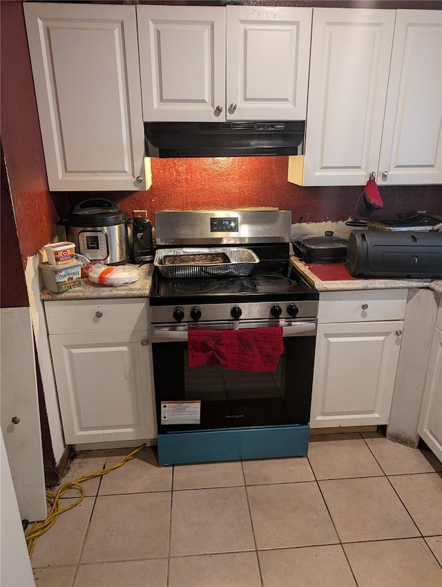 5195 Edwina St, Orlando, FL 32811 - kitchen with under cabinet range hood, stainless steel electric range, white cabinetry, and light tile patterned flooring