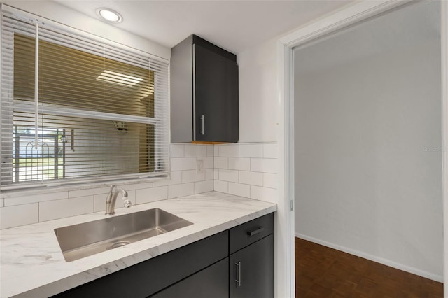 3140 Village Green Dr Unit 1119, Sarasota, FL 34239 - kitchen featuring dark cabinets, baseboards, a sink, and backsplash