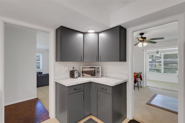 3140 Village Green Dr Unit 1119, Sarasota, FL 34239 - kitchen featuring a ceiling fan, stainless steel microwave, light stone countertops, gray cabinets, and light colored carpet