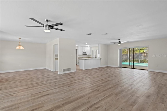 unfurnished living room with baseboards, visible vents, light wood finished floors, and ceiling fan