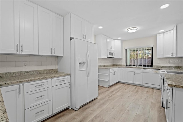 kitchen featuring light wood finished floors, tasteful backsplash, light stone counters, white cabinets, and white appliances