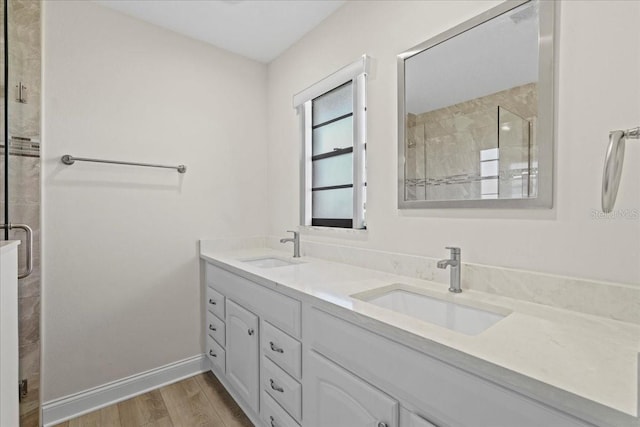 full bath featuring double vanity, a shower stall, wood finished floors, and a sink