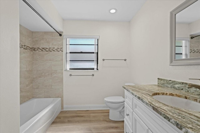 bathroom featuring toilet, wood finished floors, shower / bath combination, baseboards, and vanity