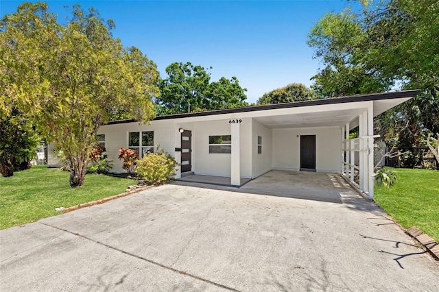 6639 16th St N, Saint Petersburg, FL 33702 - view of front of house featuring a front yard, a carport, driveway, and stucco siding