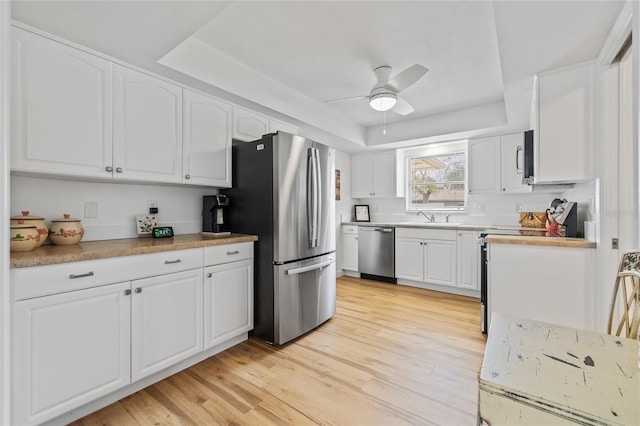 3611 22nd Ave W, Bradenton, FL 34205 - kitchen featuring appliances with stainless steel finishes, a raised ceiling, a ceiling fan, white cabinetry, and light wood-style floors