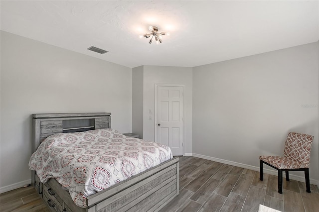 bedroom with wood finished floors, visible vents, and baseboards