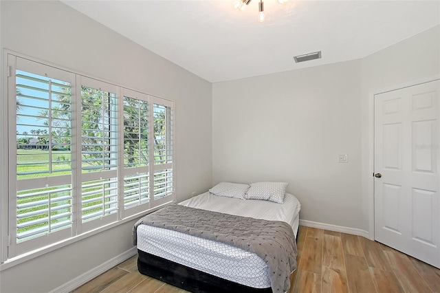 bedroom with visible vents, light wood-type flooring, and baseboards