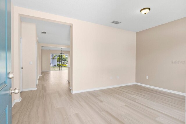 11790 Fennemore Way, Parrish, FL 34219 - empty room featuring visible vents, light wood-style flooring, baseboards, and a notable chandelier