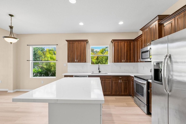 11790 Fennemore Way, Parrish, FL 34219 - kitchen with a kitchen island, light countertops, a sink, light wood finished floors, and stainless steel appliances