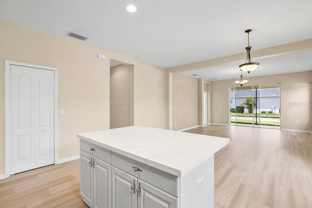 11790 Fennemore Way, Parrish, FL 34219 - kitchen featuring light wood-style flooring, a center island, open floor plan, baseboards, and visible vents