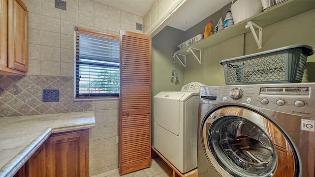 5630 Golf Pointe Dr Unit 205, Sarasota, FL 34243 - laundry room featuring visible vents, light tile patterned floors, tile walls, laundry area, and washing machine and clothes dryer