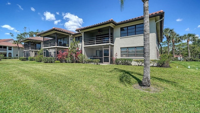 5630 Golf Pointe Dr Unit 205, Sarasota, FL 34243 - back of house with stucco siding, a ceiling fan, a lawn, and a tile roof
