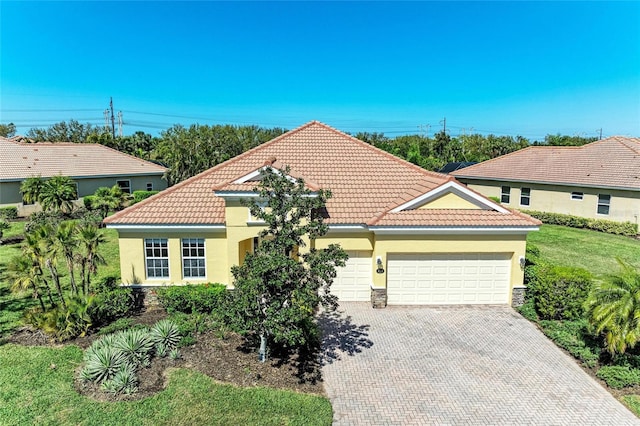 mediterranean / spanish home with decorative driveway, a garage, a tile roof, and stucco siding