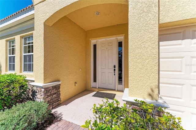 entrance to property with stucco siding, a tiled roof, and a garage