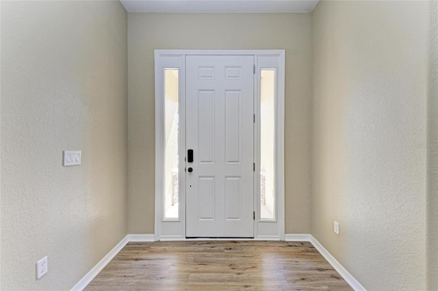 entryway featuring wood finished floors, baseboards, and a textured wall