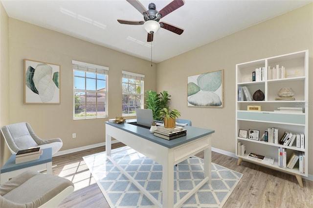 office space with baseboards, light wood-type flooring, and ceiling fan