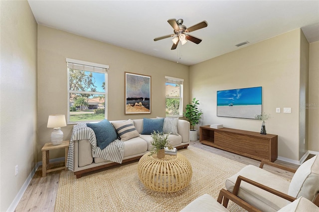 living room with visible vents, baseboards, wood finished floors, and a ceiling fan