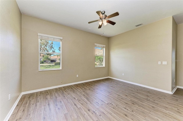empty room with baseboards, wood finished floors, visible vents, and ceiling fan