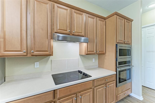 kitchen featuring light wood-type flooring, under cabinet range hood, appliances with stainless steel finishes, light countertops, and baseboards