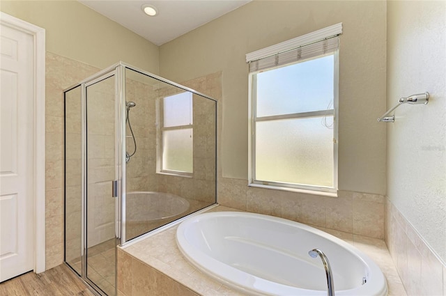 bathroom with wood finished floors, a garden tub, and a stall shower