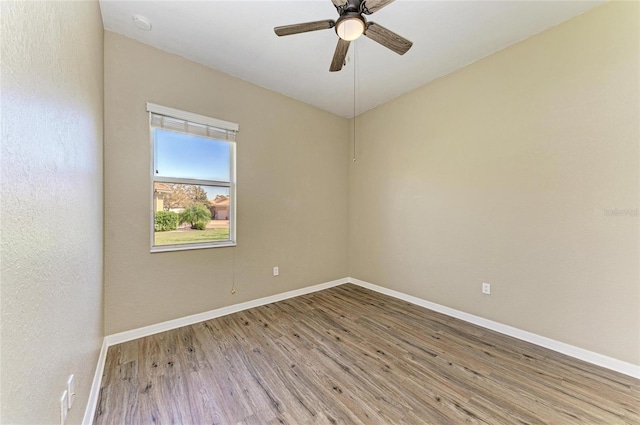 unfurnished room featuring a ceiling fan, wood finished floors, and baseboards