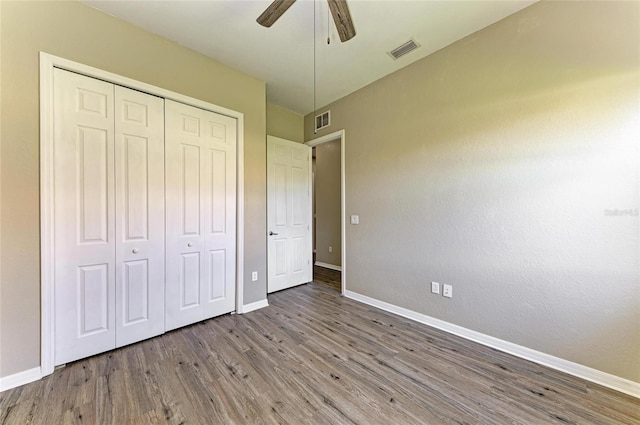 unfurnished bedroom featuring visible vents, baseboards, a closet, and wood finished floors