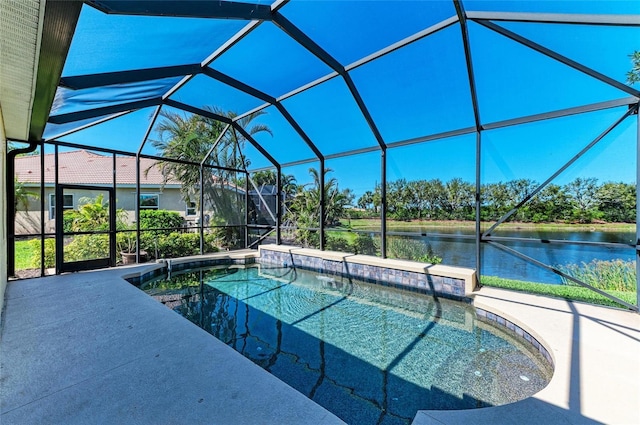 outdoor pool with glass enclosure, a patio area, and a water view