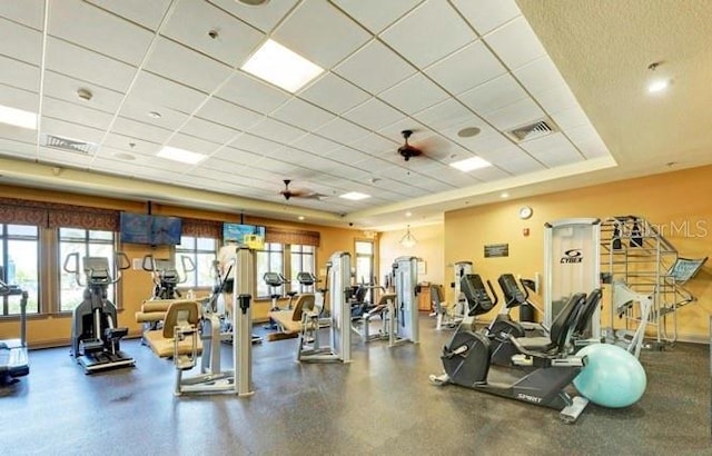 exercise room featuring a paneled ceiling, visible vents, and baseboards