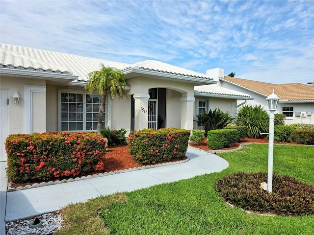 view of front of home with stucco siding, a front lawn, and a tiled roof