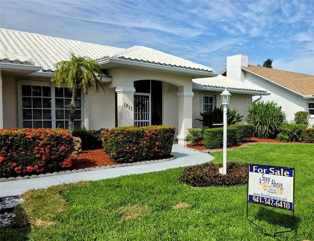 exterior space with a tile roof, a front yard, and stucco siding