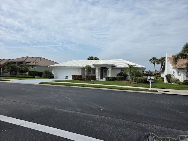 ranch-style house with an attached garage, driveway, a tiled roof, and a front lawn