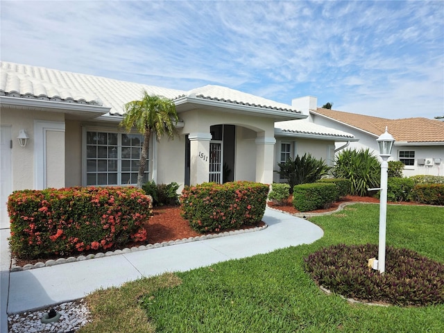 view of front of house with a tiled roof, a front yard, and stucco siding
