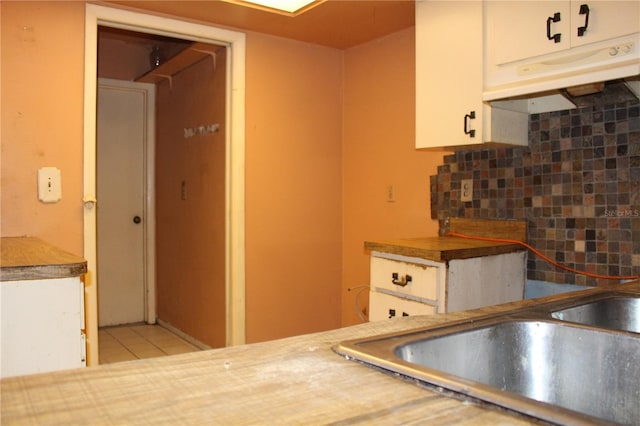 1862 Orangewood Ln, Sarasota, FL 34232 - kitchen with a sink, tile patterned flooring, decorative backsplash, white cabinets, and under cabinet range hood