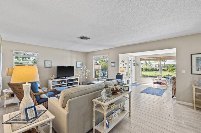 7122 11th Ave W, Bradenton, FL 34209 - living room featuring baseboards, visible vents, a textured ceiling, and light wood-style floors