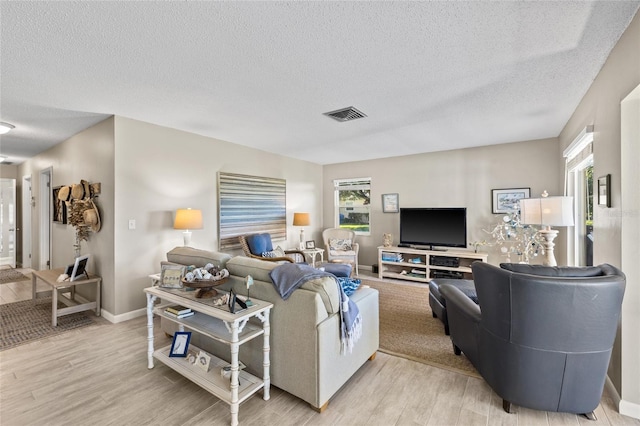 7122 11th Ave W, Bradenton, FL 34209 - living room featuring a textured ceiling, baseboards, visible vents, and light wood-type flooring